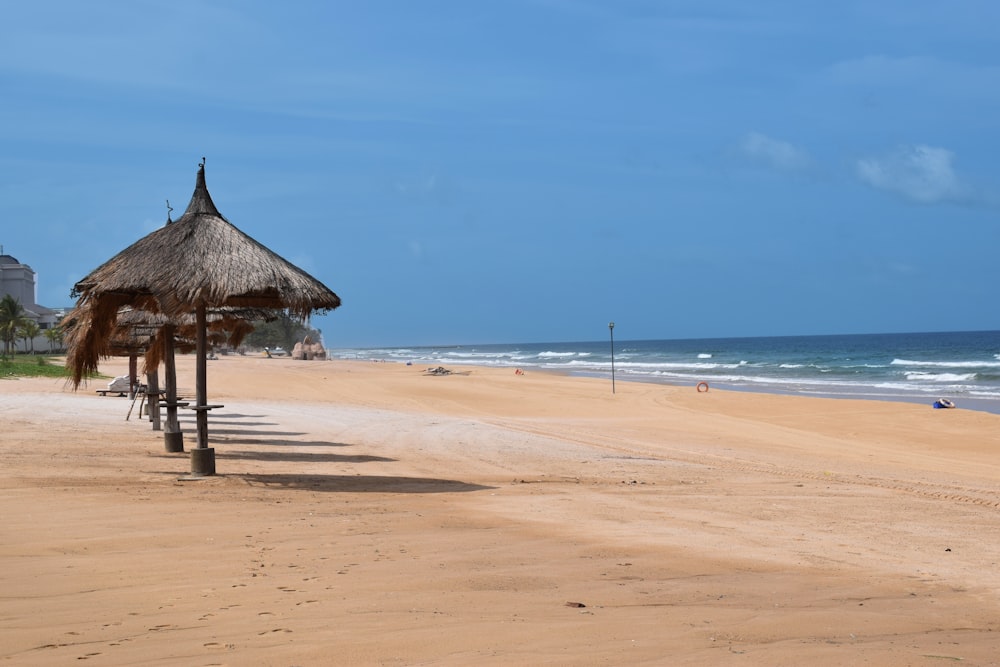 brown wooden beach house on brown sand near sea during daytime