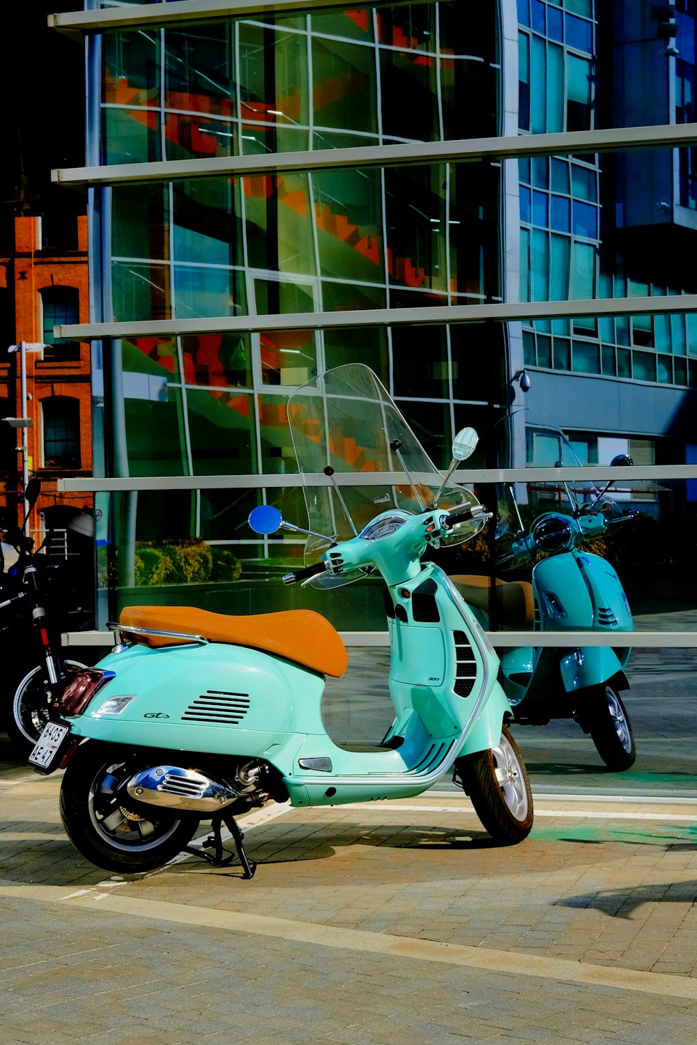 white and blue motor scooter parked beside glass building during daytime