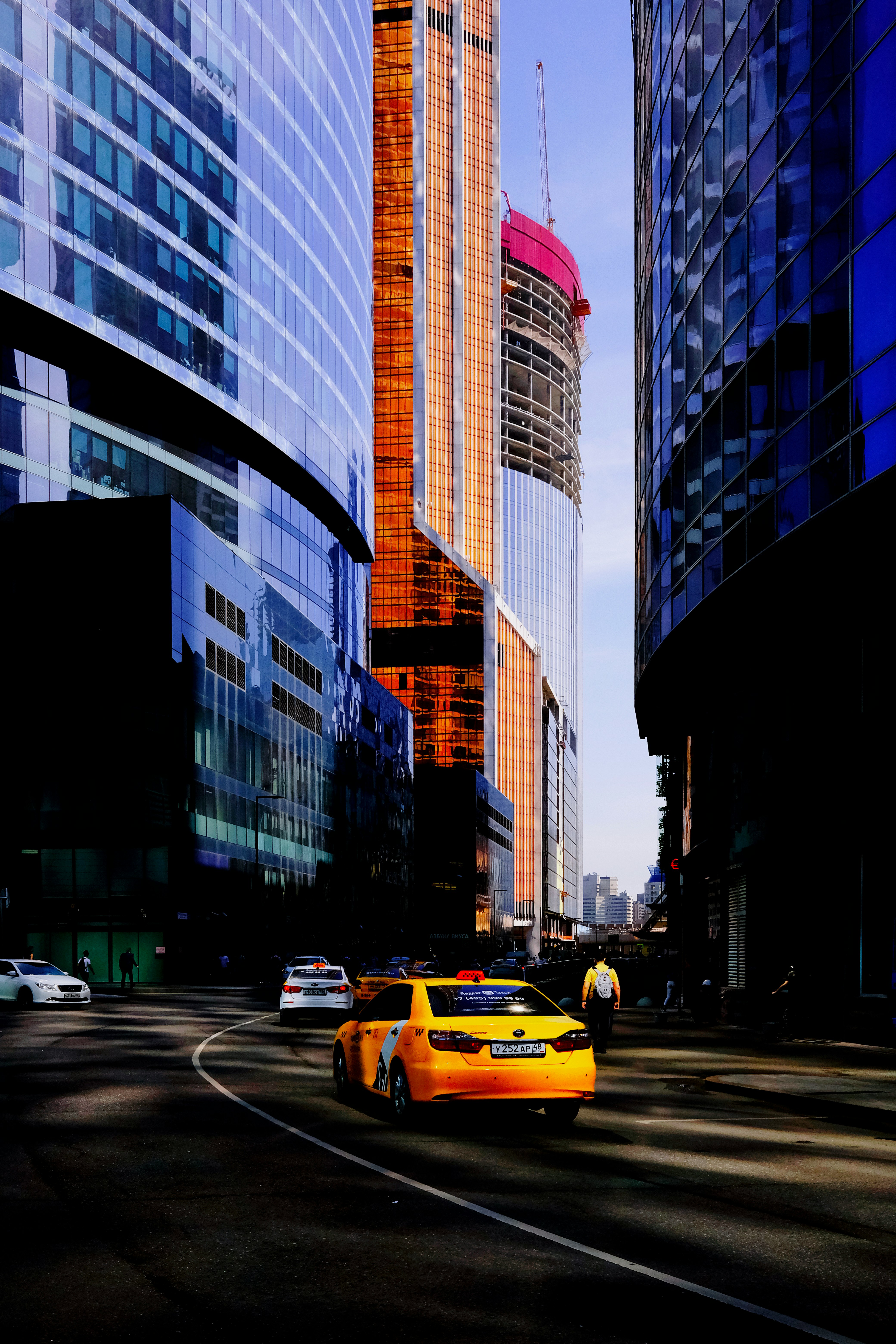 yellow taxi on road near high rise buildings during daytime