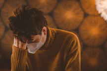 man in brown coat wearing white face mask