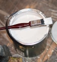 red handle paint brush in white paint bucket