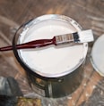 red handle paint brush in white paint bucket