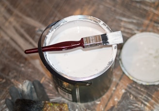 red handle paint brush in white paint bucket