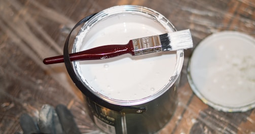 red handle paint brush in white paint bucket