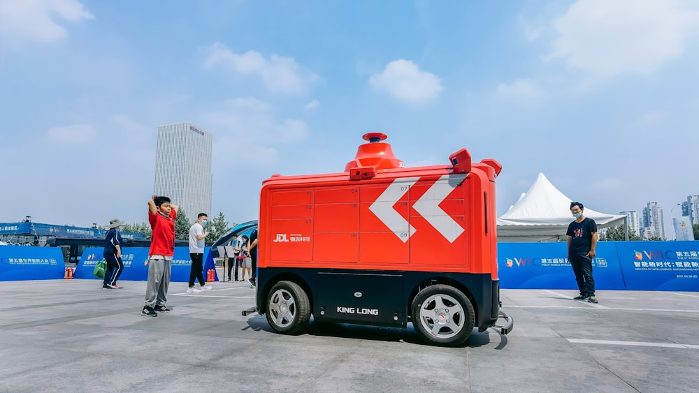 man in white shirt and black pants standing beside red truck