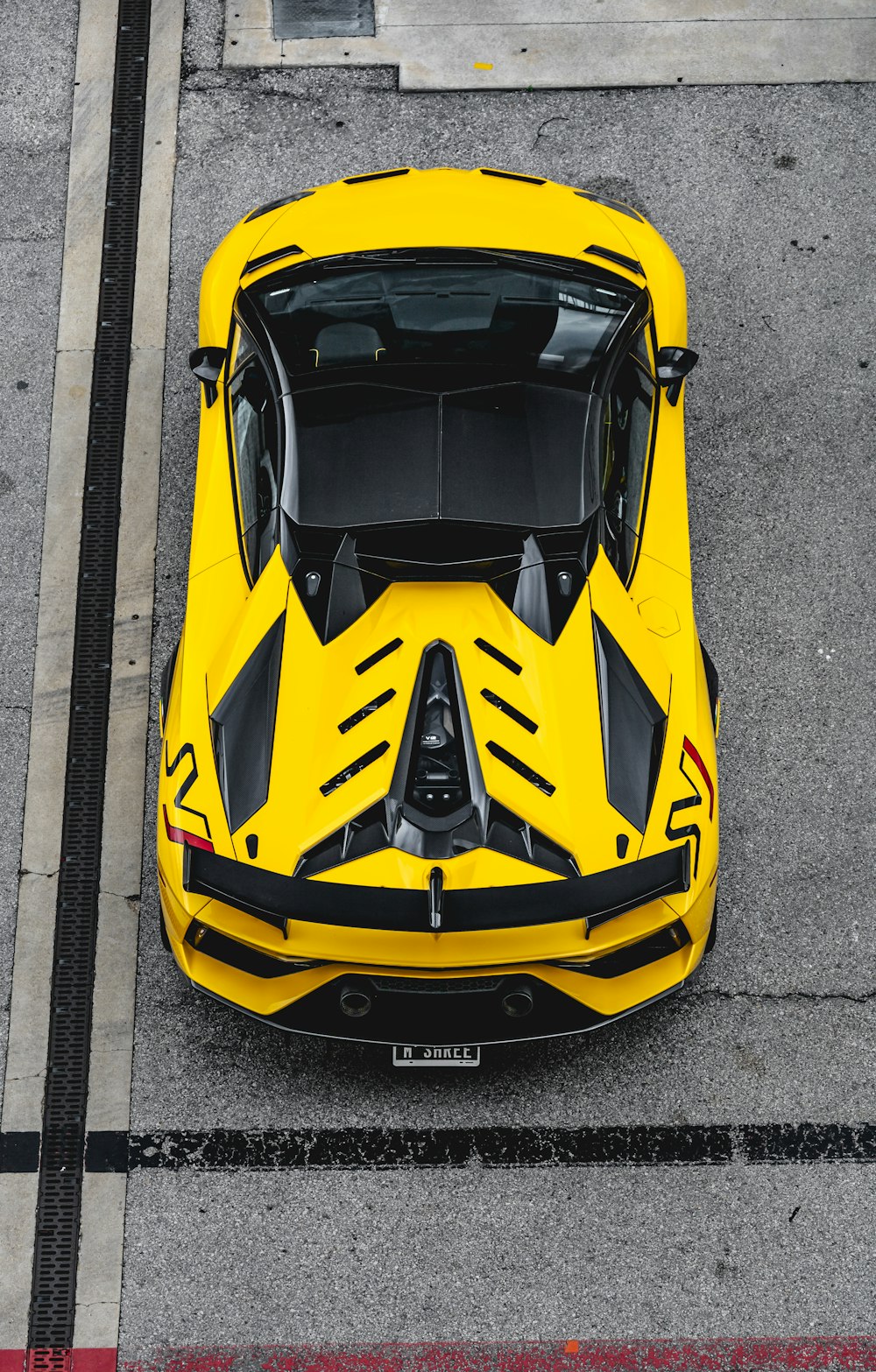 Gelber und schwarzer Lamborghini Aventador tagsüber auf grauer Betonstraße geparkt