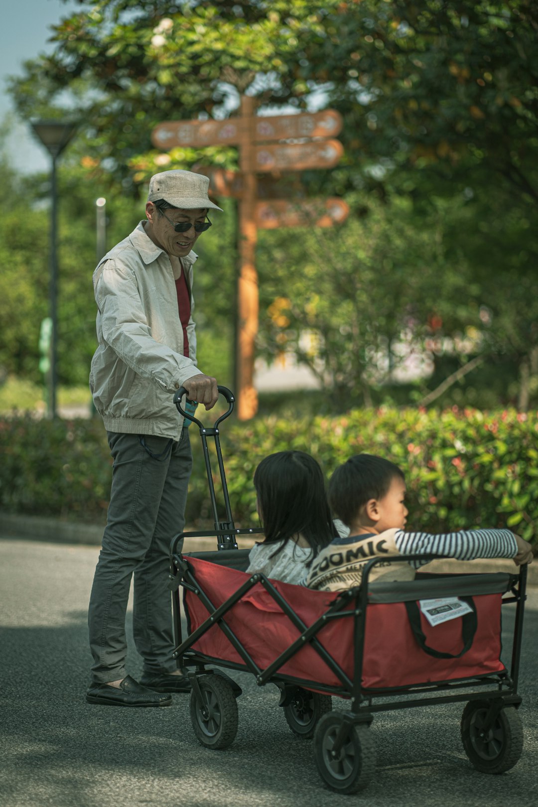 man in white dress shirt and brown hat sitting on red and black stroller during daytime