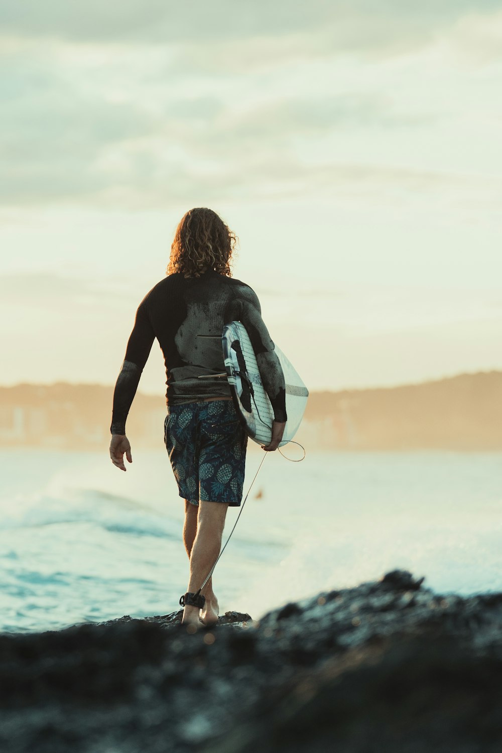 woman in black long sleeve shirt and blue denim shorts standing on rock near body of on on on on