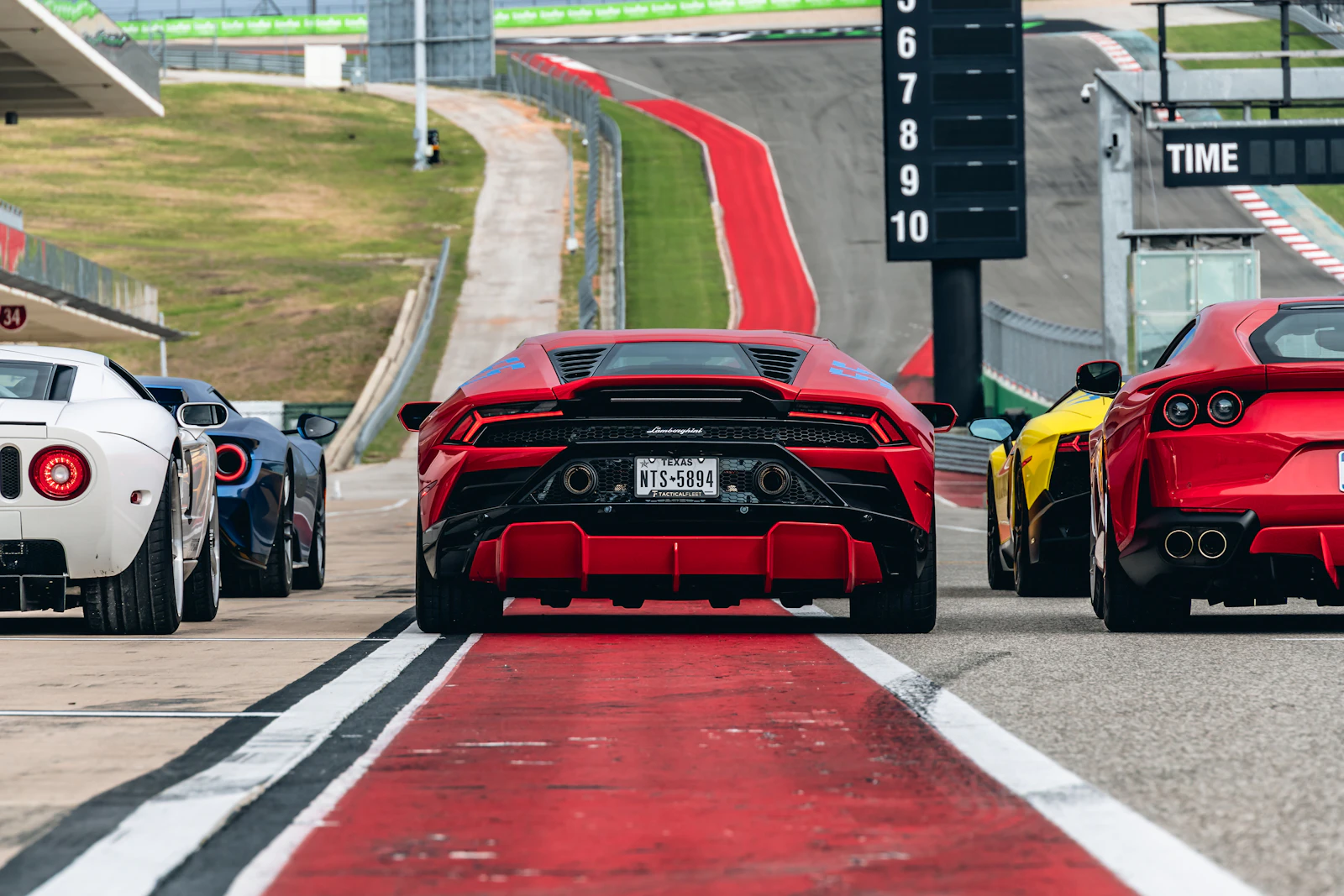 Red Lamborghini Huracan and a red Ferrari lined up in a race track pit lane