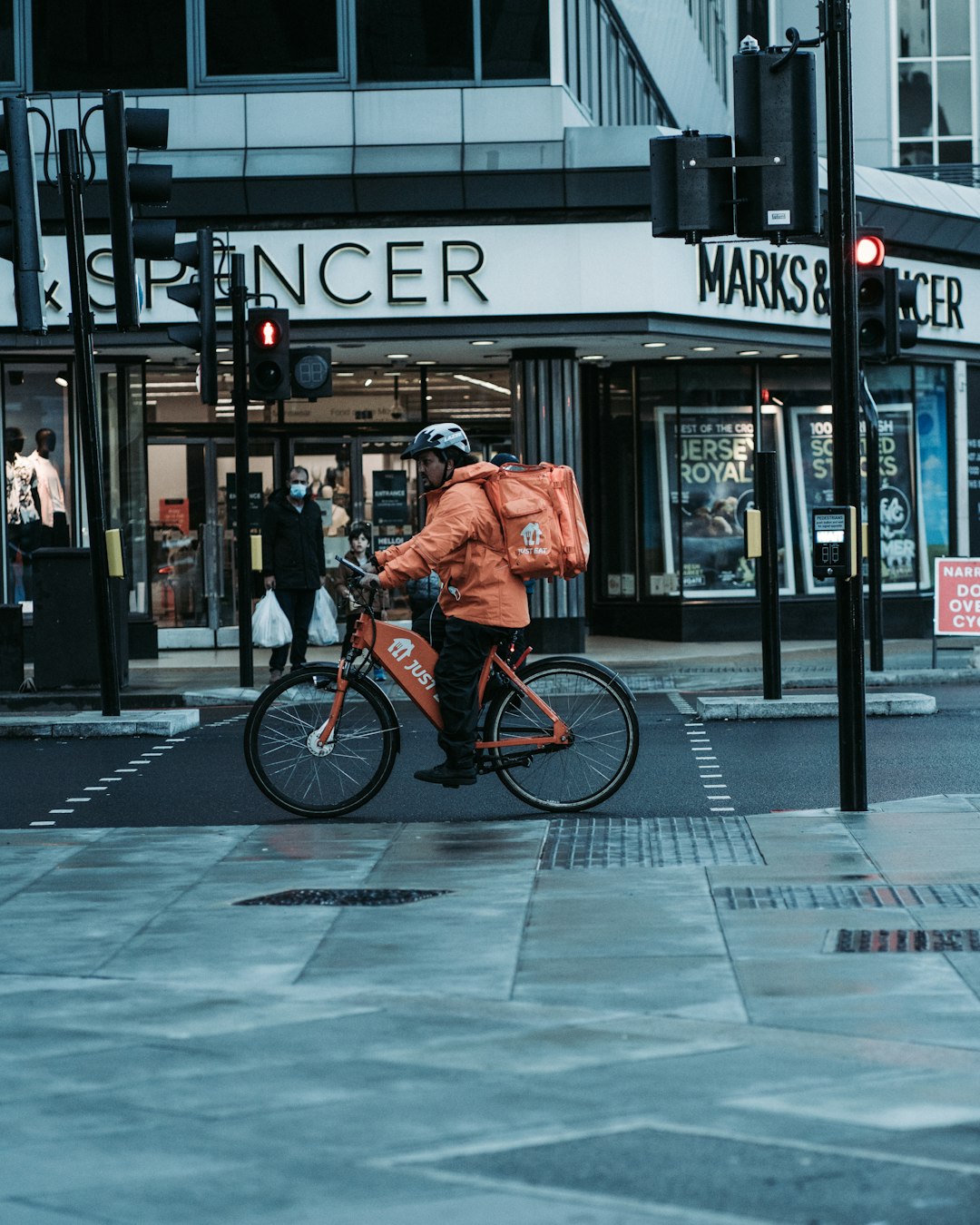 man in orange jacket riding bicycle on road during daytime