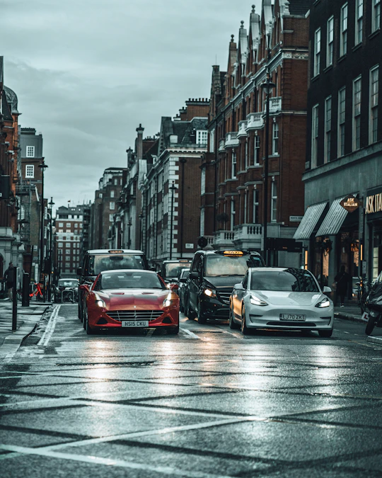 red car on road between high rise buildings during daytime