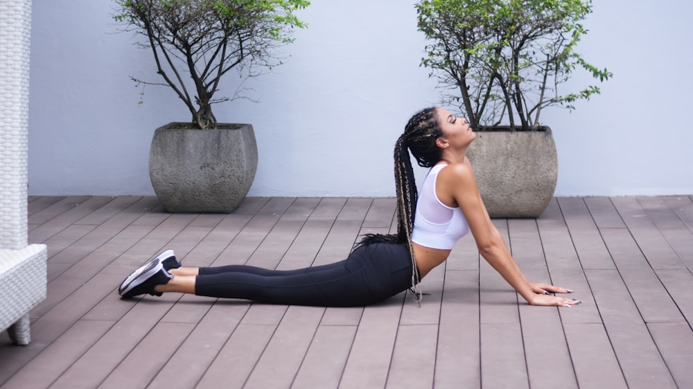 mujer con sujetador deportivo blanco y leggings negros haciendo yoga