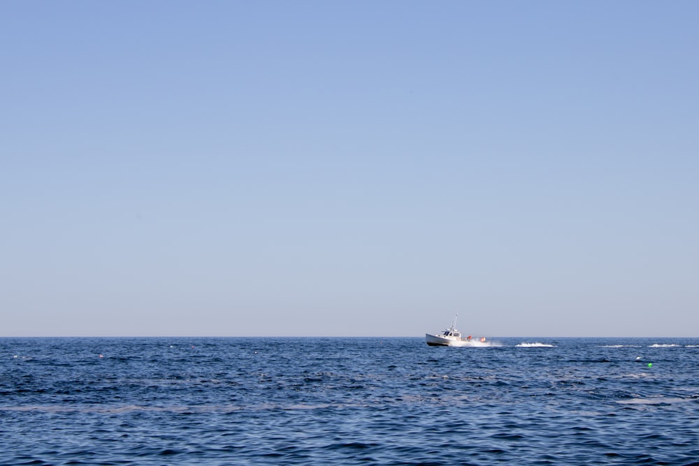 昼間、灰色の空の下で海に浮かぶ白いボート