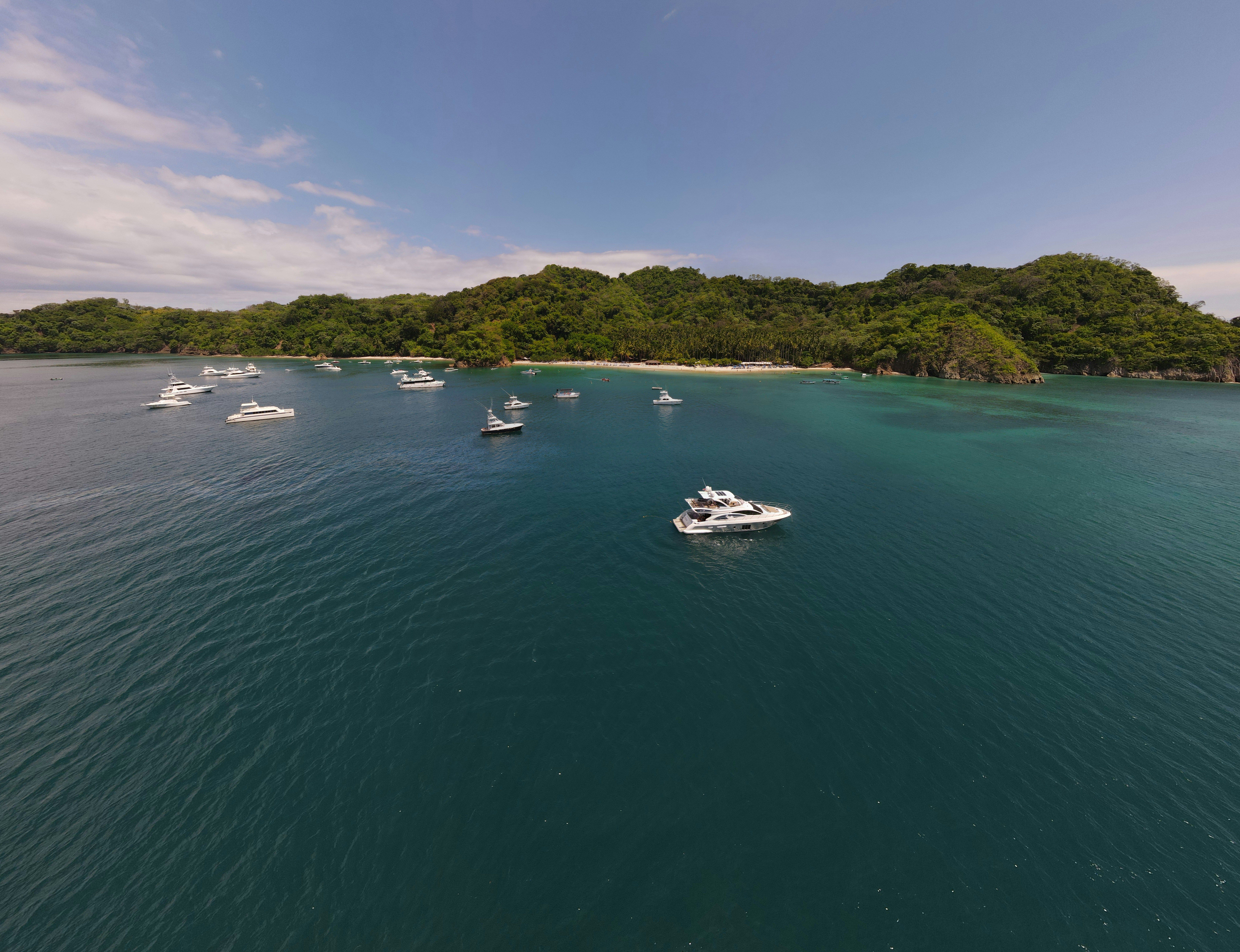 white boat on sea near green mountain during daytime