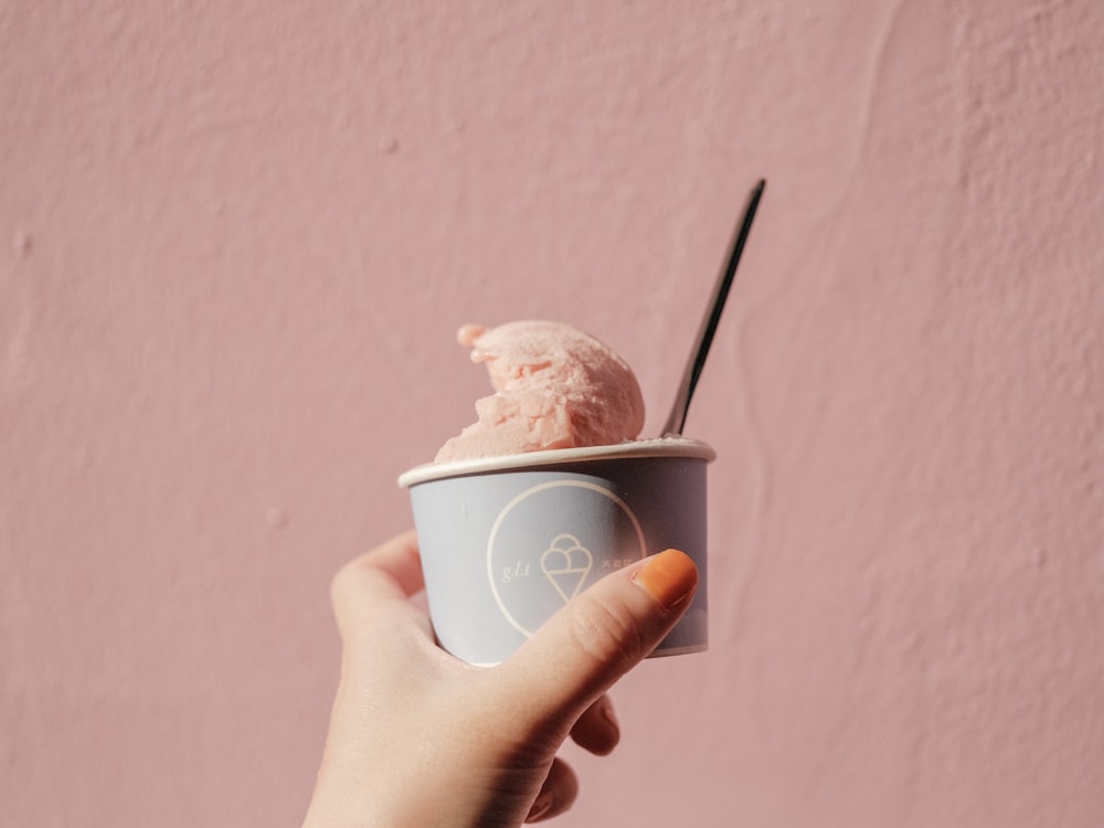 Persona che tiene la tazza usa e getta bianca con il gelato