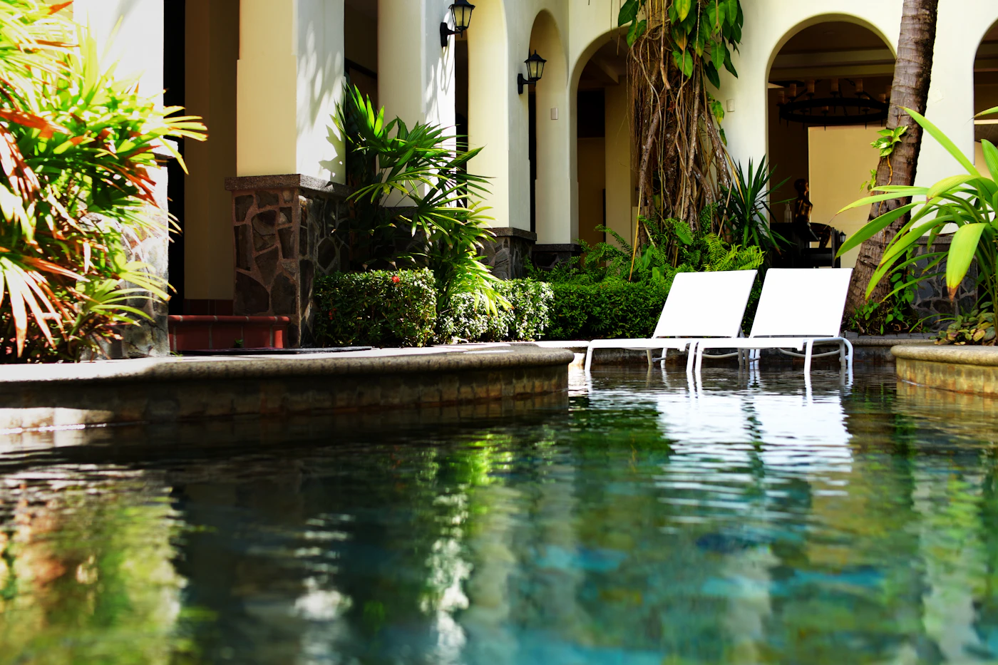 Stone coping and arches beside a lush garden pool