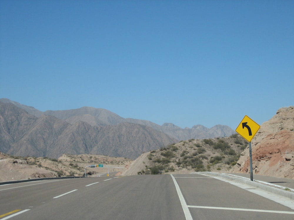 gray concrete road near mountain during daytime