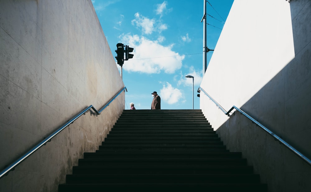 man in brown jacket sitting on stairs during daytime