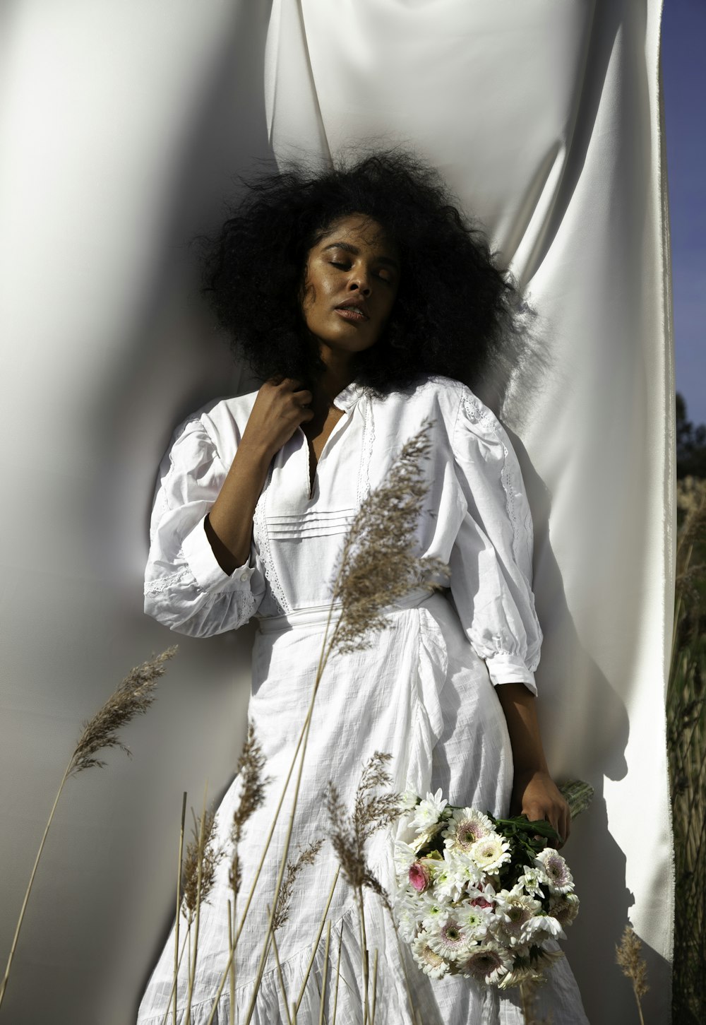 woman in white long sleeve shirt holding white flowers