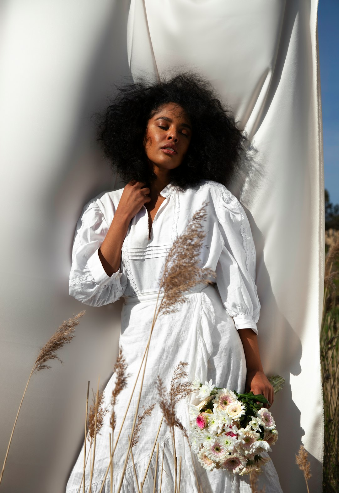 woman in white long sleeve shirt holding white flowers