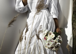 woman in white long sleeve shirt holding white flowers