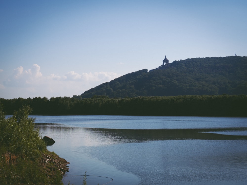 green mountain beside lake under blue sky during daytime