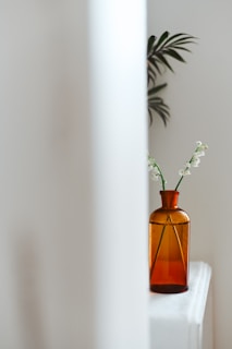 Minimalist shot of a jasmine oud attar bottle beside fresh jasmine flowers on a smooth beige surface.