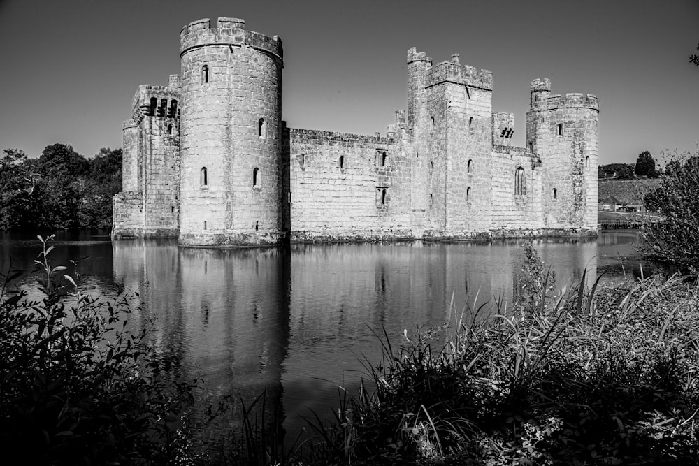 grayscale photo of concrete building near body of water