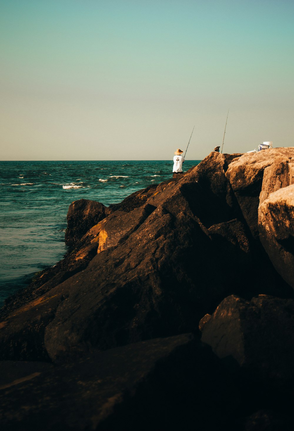 person standing on rock formation near body of water during daytime