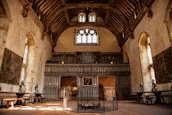 An inviting interior of a guild hall with wooden beams and a warm fireplace.
