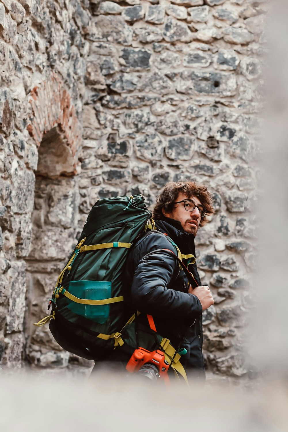 Mann in schwarzer Jacke mit grünem Rucksack