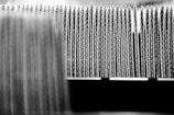 A close-up view of the edges of several stacked sheets of corrugated cardboard arranged in a row, highlighting the wavy structure of the material.