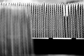A close-up view of the edges of several stacked sheets of corrugated cardboard arranged in a row, highlighting the wavy structure of the material.