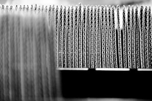A close-up view of the edges of several stacked sheets of corrugated cardboard arranged in a row, highlighting the wavy structure of the material.