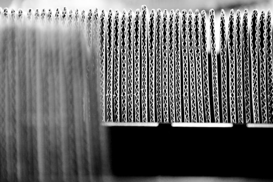 A close-up view of the edges of several stacked sheets of corrugated cardboard arranged in a row, highlighting the wavy structure of the material.
