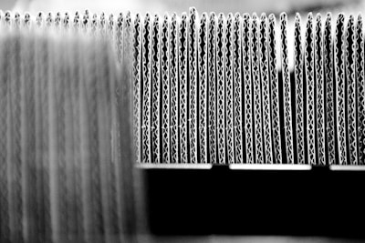 A close-up view of the edges of several stacked sheets of corrugated cardboard arranged in a row, highlighting the wavy structure of the material.