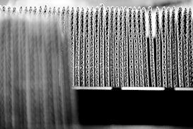 A close-up view of the edges of several stacked sheets of corrugated cardboard arranged in a row, highlighting the wavy structure of the material.