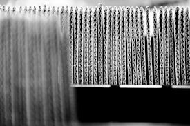 A close-up view of the edges of several stacked sheets of corrugated cardboard arranged in a row, highlighting the wavy structure of the material.