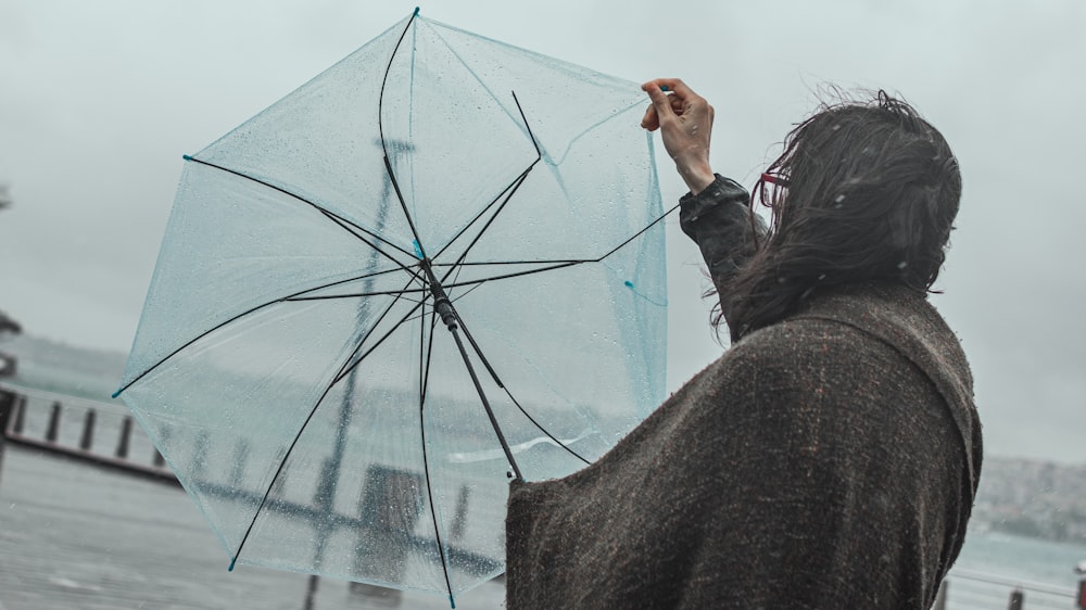 Frau in schwarzer Jacke mit Regenschirm