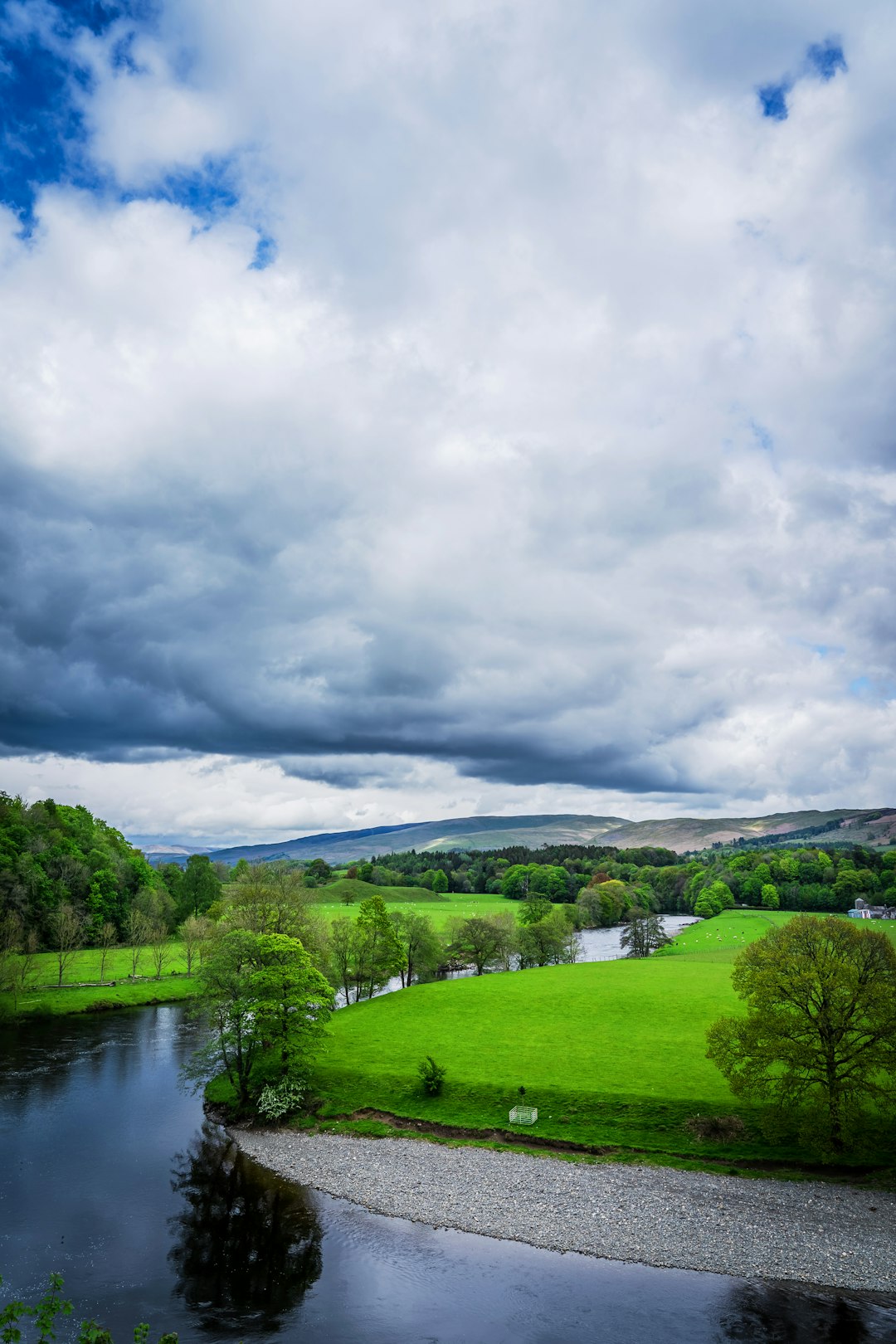 green grass field near river under cloudy sky during daytime