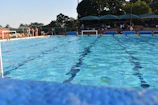Team of lifeguards standing by the edge of a sparkling blue swimming pool during a maintenance break.