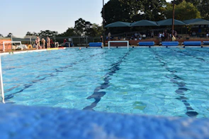 Team of lifeguards standing by the edge of a sparkling blue swimming pool during a maintenance break.