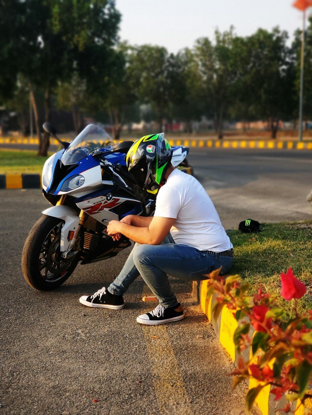 man in white shirt and blue denim jeans riding white and black sports bike