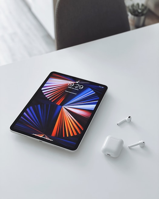 A tablet displaying a colorful digital art piece resting beside wireless headphones