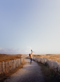 woman in blue denim jacket and blue denim jeans walking on pathway during daytime