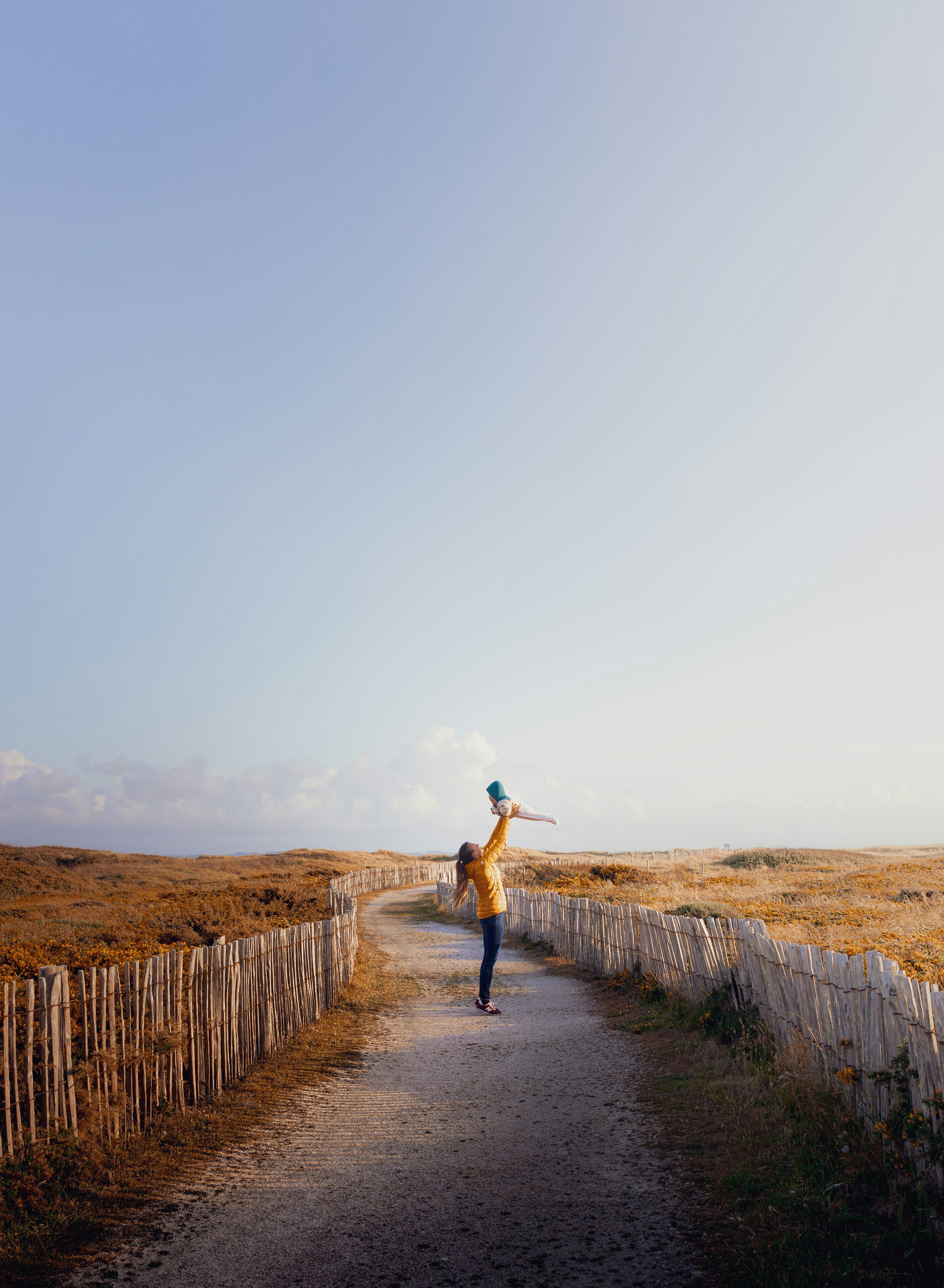 woman in blue denim jacket and blue denim jeans walking on pathway during daytime