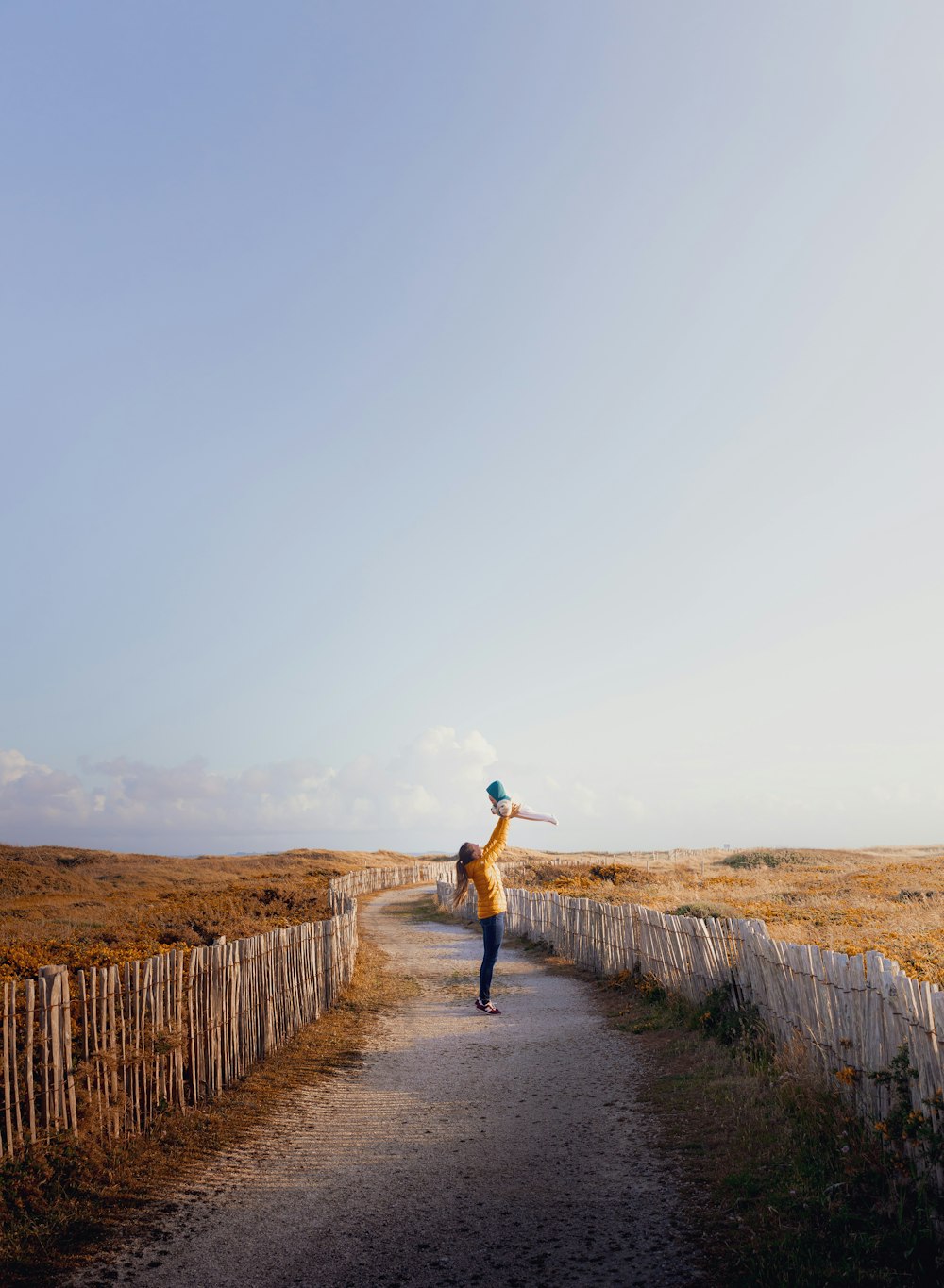 woman in blue denim jacket and blue denim jeans walking on pathway during daytime