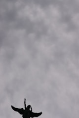 A guardian angel with glowing wings watching over a city skyline at dusk.