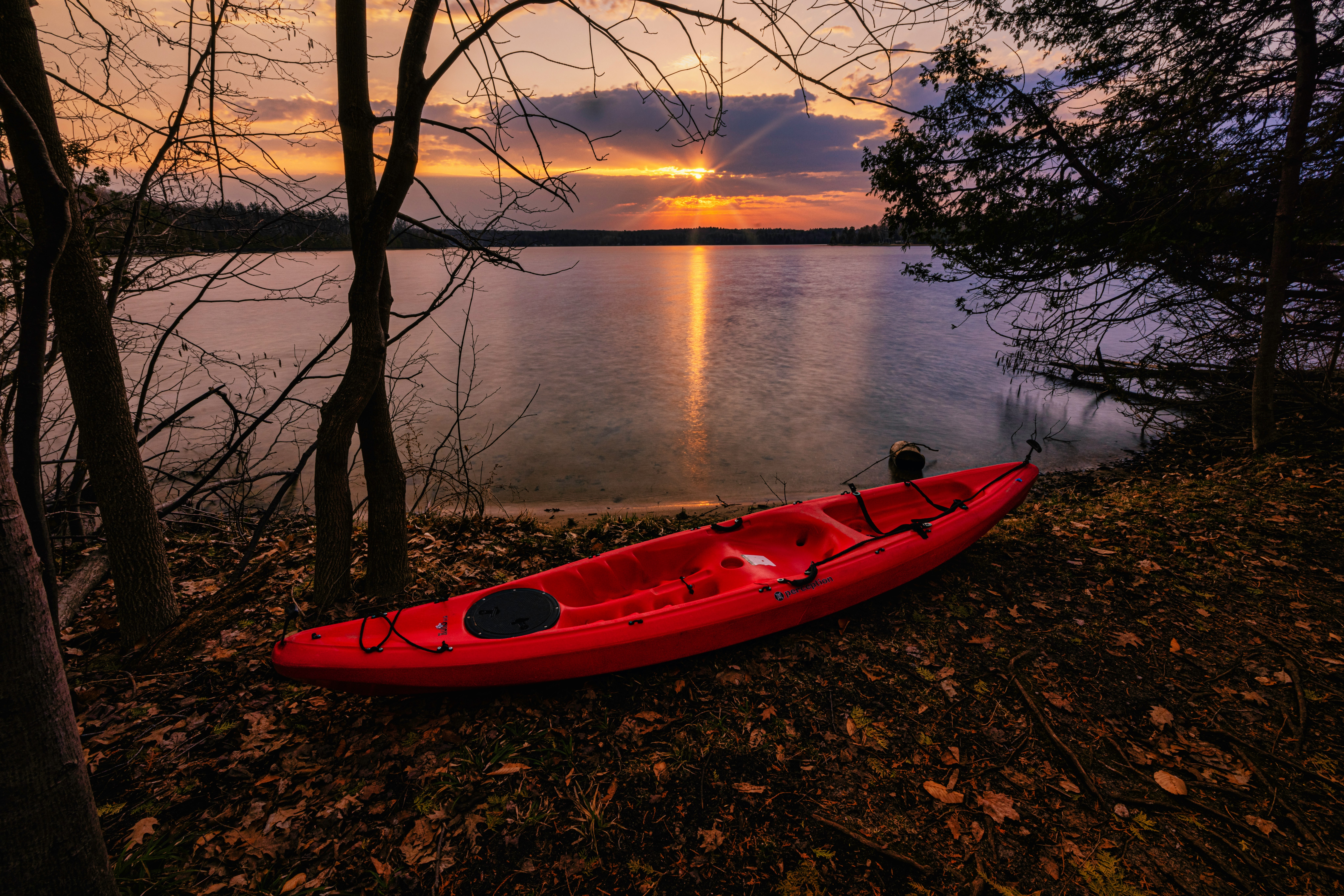 red kayak on lake during sunset