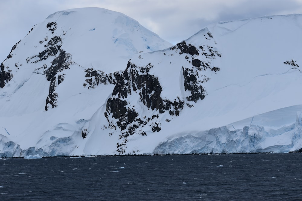 snow covered mountain near body of water during daytime